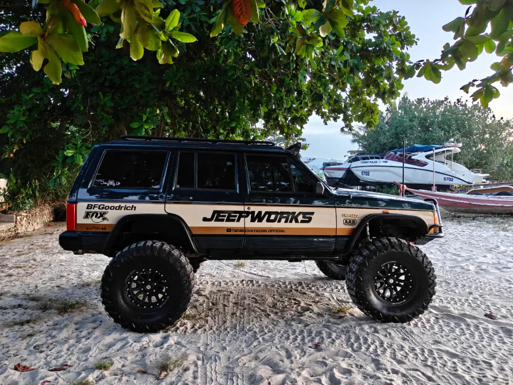 Green Hulk lifted Jeep in side profile on the sand beneath a tree