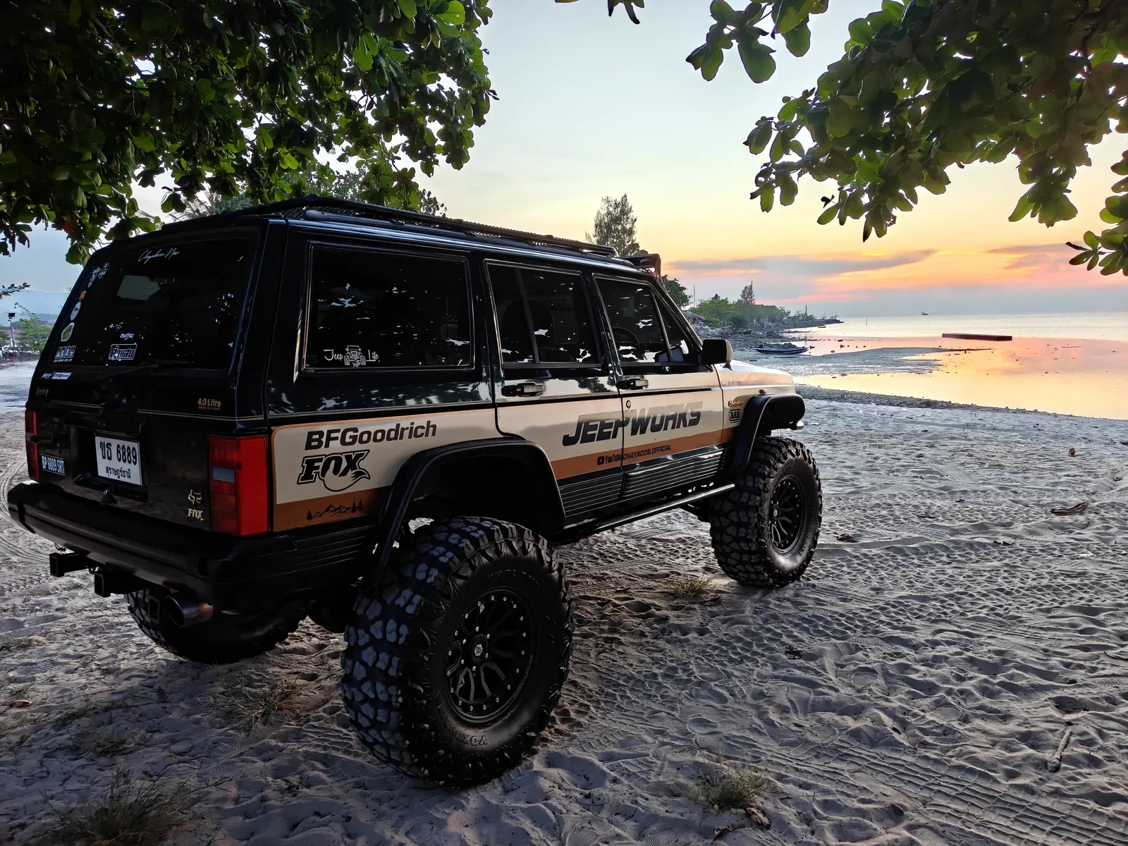 Green Hulk Jeep in rear three-quarter view beside the sea at sunset