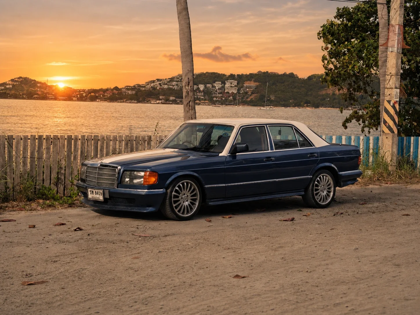 Classic Mercedes-Benz 500 SE parked by the sea at golden hour on Koh Samui