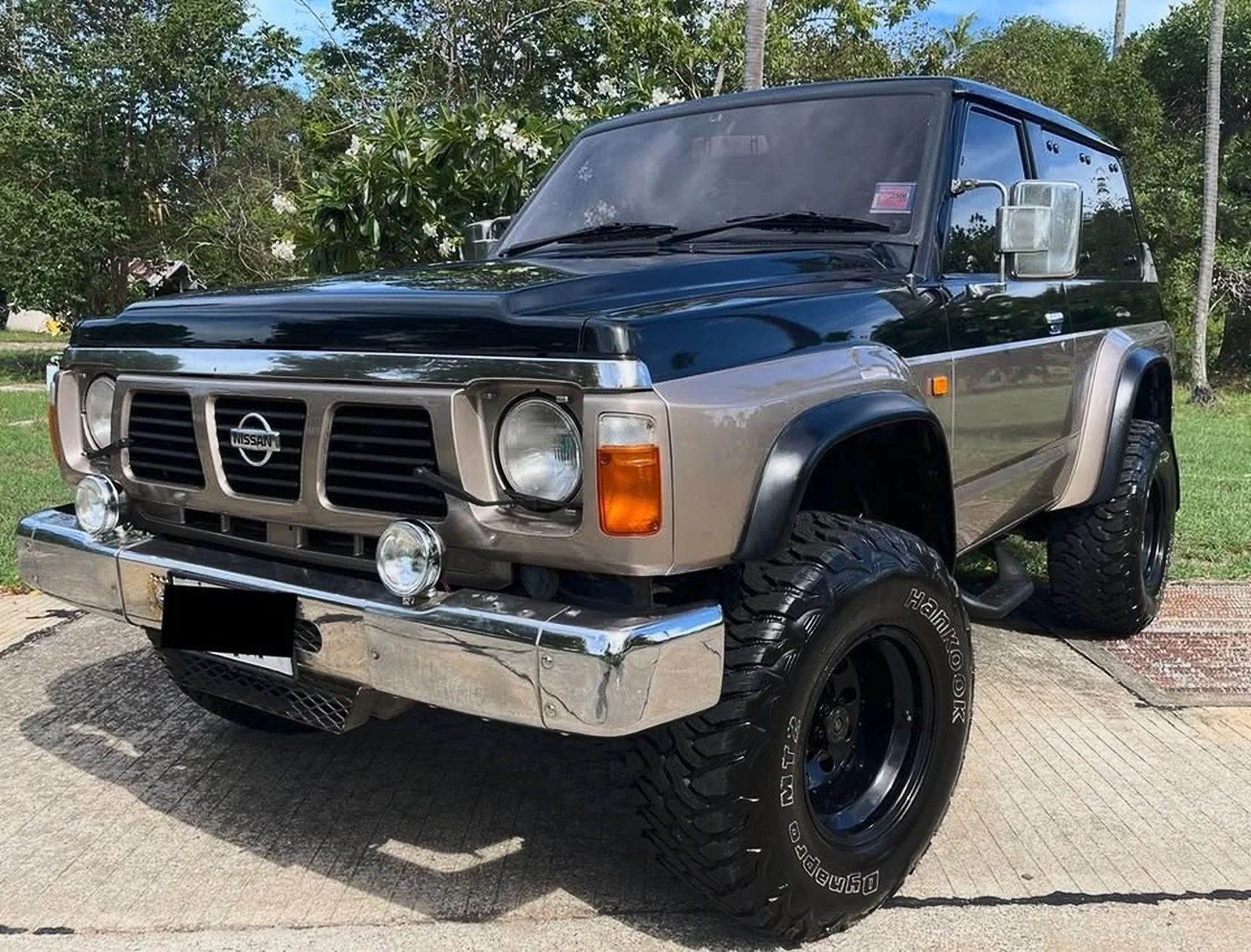 Nissan Patrol Y60 Safari de 1990 negro y gris de batalla corta, en vista tres cuartos delantera en Koh Samui