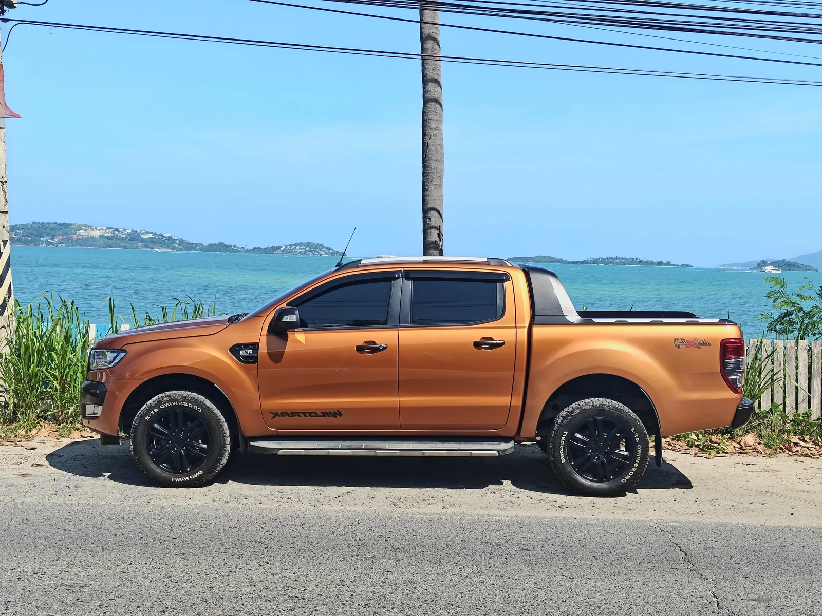 Оранжевый Ford Ranger Wildtrak 3.2 2015 года с двойной кабиной, вид сбоку у моря на Самуи