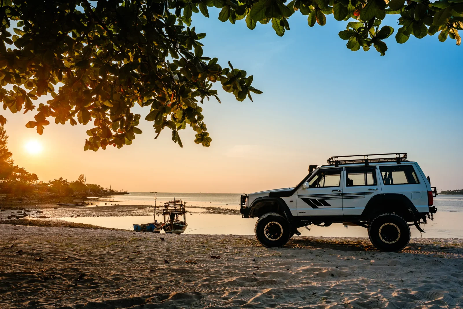 White Samurai modified Jeep in warm evening light beside the sea